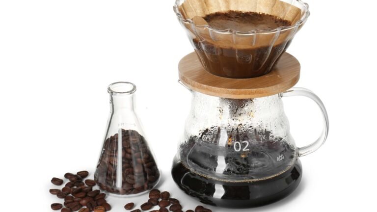 The photo shows a science beaker containing coffee beans, and hot water being poured over coffee beans through a paper filter into a larger beaker