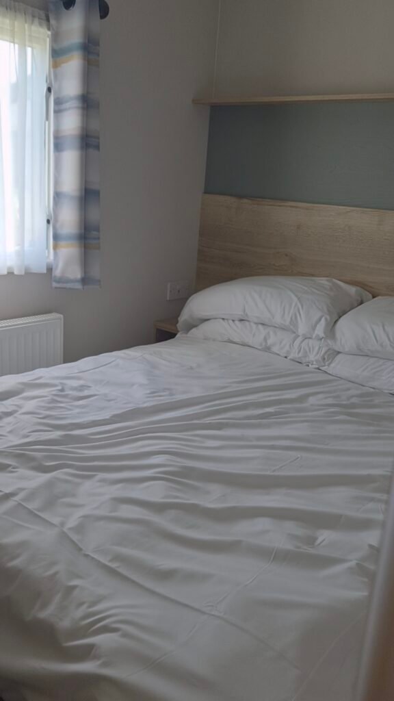 The photo shows a small double bed with white linen. It looks clean and neat